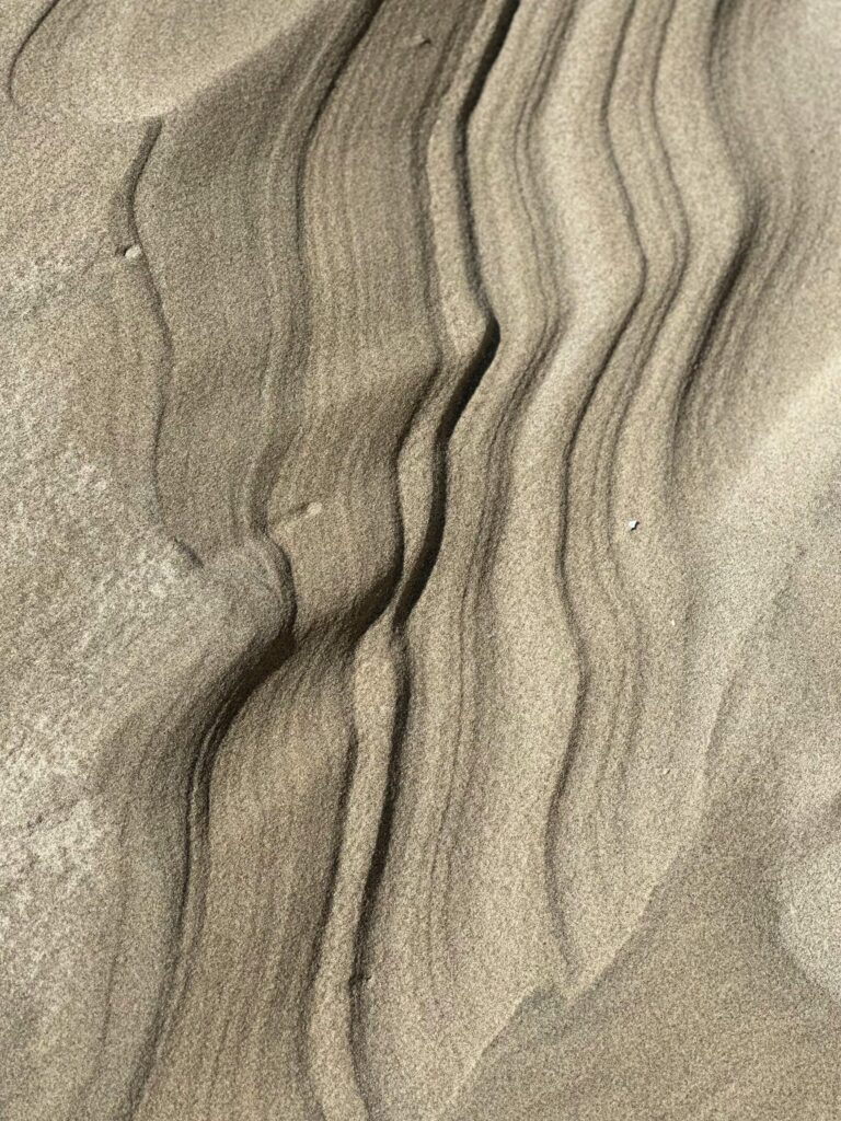Close-up of natural sand ripples showcasing elegant patterns and textures formed by the wind in a desert landscape.